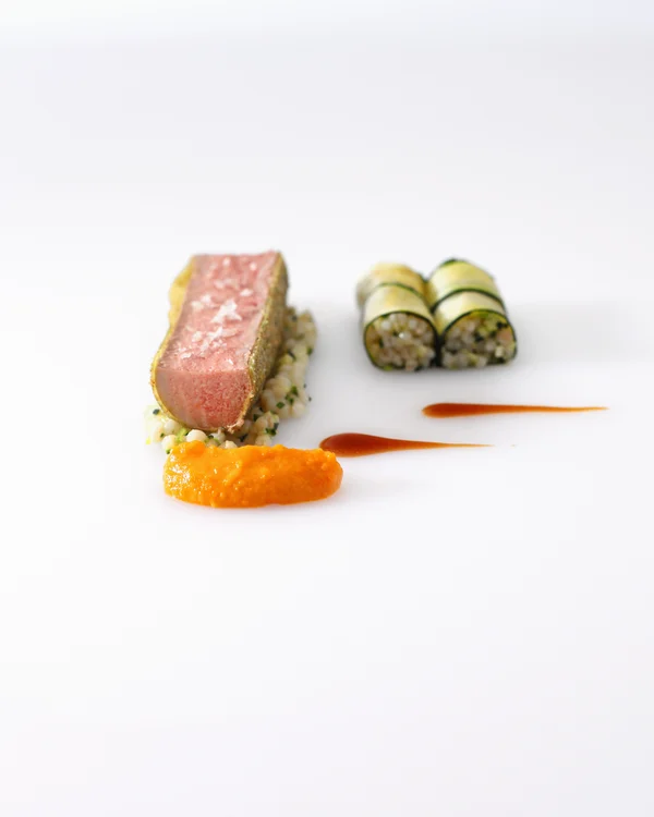 What’s a party without great food and the perfect drink? Elegantly plated dish with meat, vegetables, and sauces on white plate