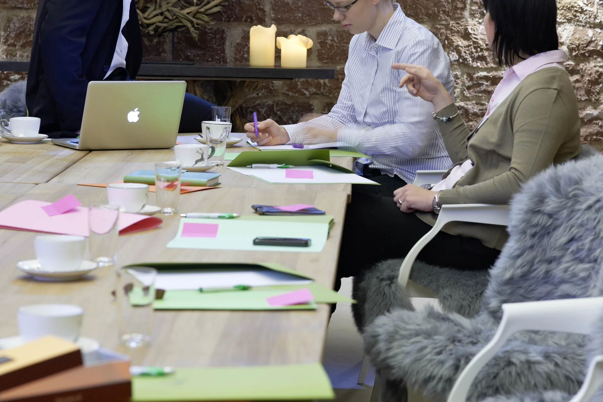 Ihr Tagungshotel Pfalz | Kreative Meetings im historischen Kloster Hornbach Drei Personen bei Besprechung an einem Tisch mit Laptop und Notizen
