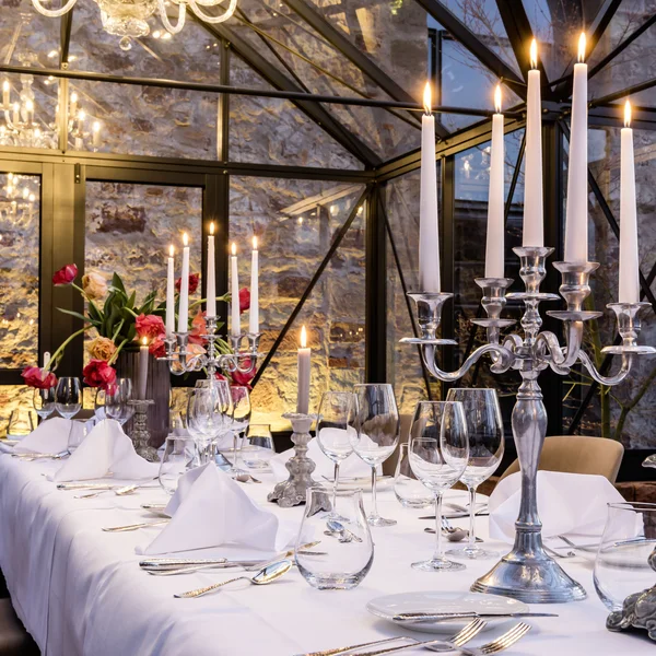 Treffpunkt, Kraftplatz und Hotel in Hornbach Fein gedeckter Tisch mit Kerzen in elegantem Glasgewächshaus vor Steinwand