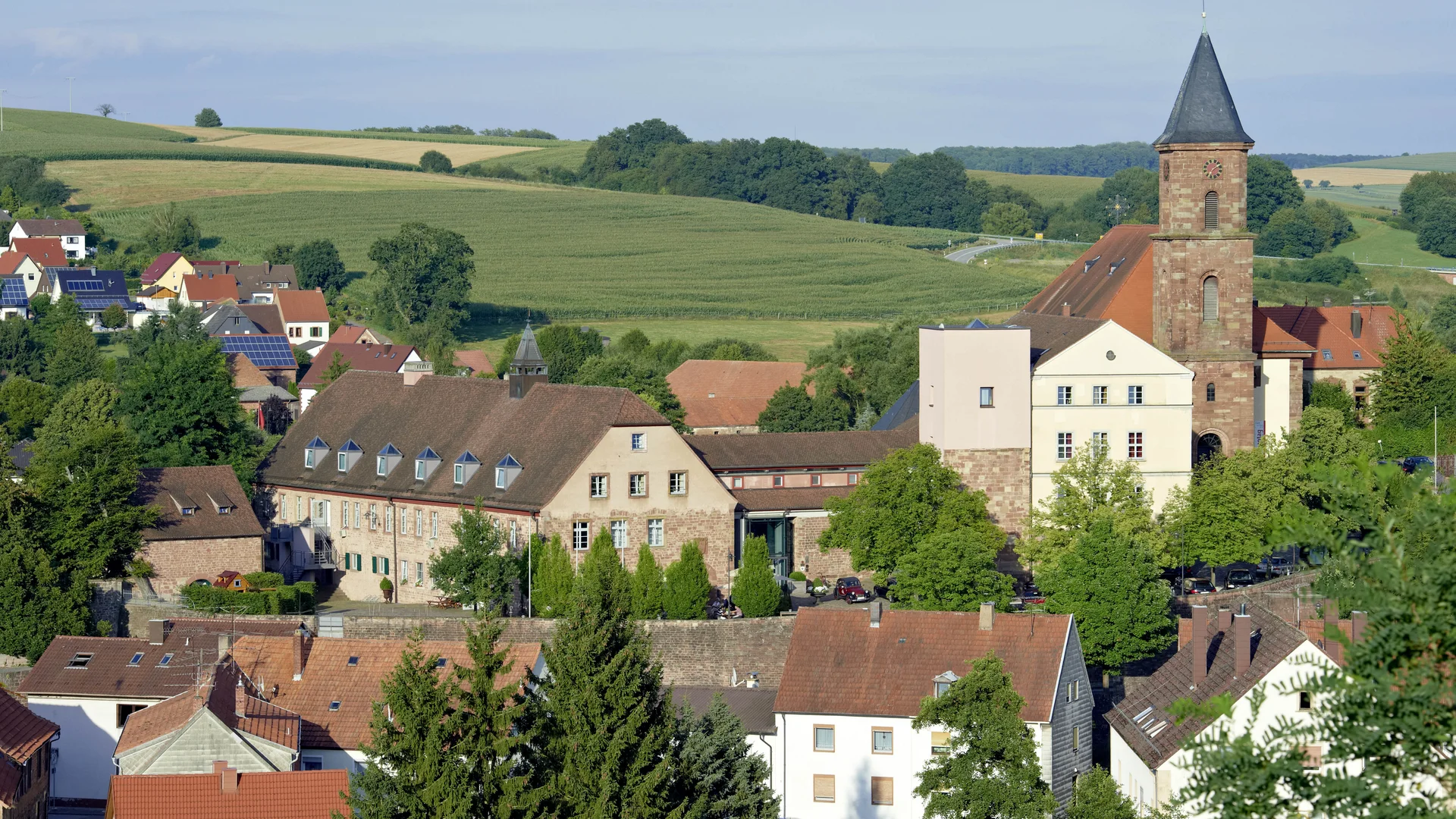 Treffpunkt, Kraftplatz und Hotel in Hornbach Dorf mit Kirche und Häusern umgeben von grünen Feldern und Hügeln