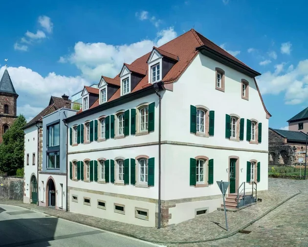 Treffpunkt, Kraftplatz und Hotel in Hornbach Historisches Gebäude mit grünem Fensterläden und rotem Dach an einer Kopfsteinpflasterstraße