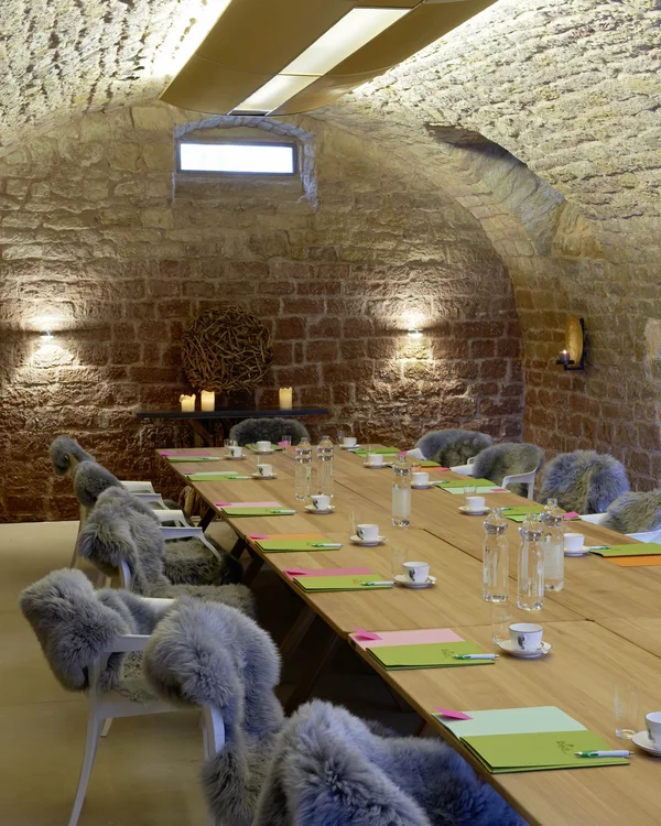 Ihr Tagungshotel Pfalz | Kreative Meetings im historischen Kloster Hornbach Konferenzraum mit langem Holztisch und Stühlen mit Fellbezügen in einem Gewölbe