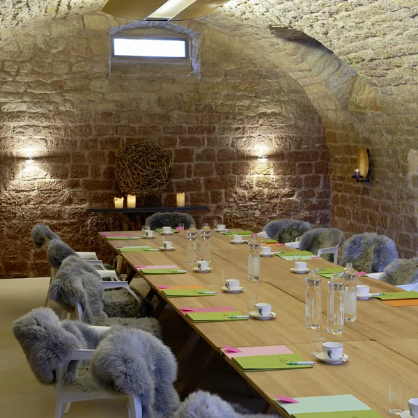 Exzellenter Lernort Kloster Hornbach Konferenzraum mit langem Holztisch und Stühlen mit Fellbezügen in einem Gewölbe