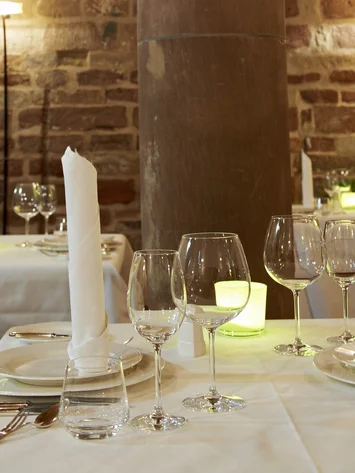 Räume für besondere Anlässe im Kloster Hornbach Elegantes Restaurant mit gedeckten Tischen und Steinpfeiler im Innenraum