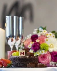 Kloster Hornbach: Ihre Ansprechperson für Medienanfragen Schokoladenkuchen mit Früchten, Kerze, Sektgläser und Blumenstrauß auf Tisch