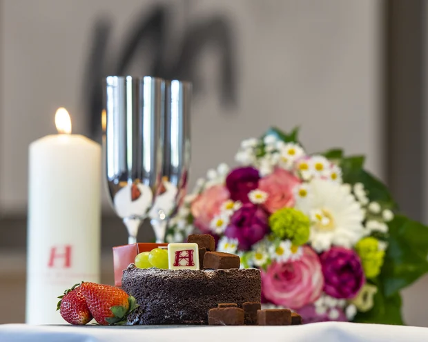 Our venue, your dream wedding Chocolate cake with fruit, candle, champagne glasses and bouquet on table