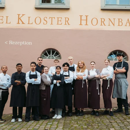 Veranstaltungen im Kloster Hornbach Hotel Kloster Hornbach Team steht vor dem Hotelfassade mit Empfangsschild