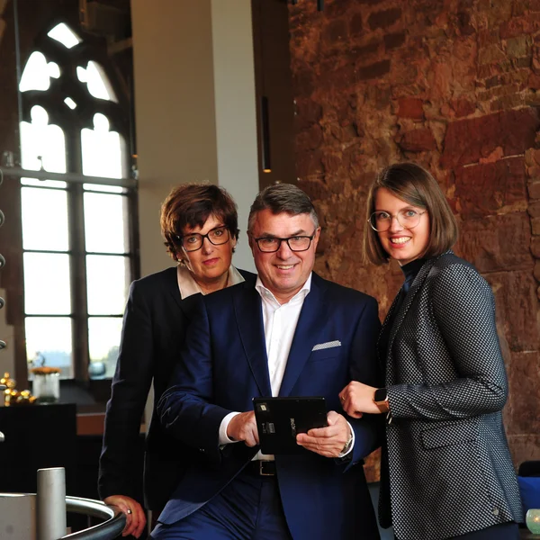 Treffpunkt, Kraftplatz und Hotel in Hornbach Drei Geschäftsleute lächeln, während sie gemeinsam ein Tablet benutzen