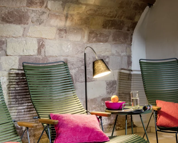Wellness im Kloster in Deutschland Grüne Liegestühle mit pinken Kissen und Lampe vor einer Steinwand