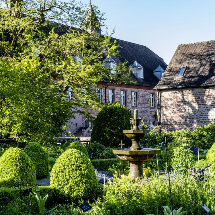 Treffpunkt, Kraftplatz und Hotel in Hornbach Historischer Garten mit Springbrunnen und Fachwerkhäusern im Hintergrund bei Sonnenschein