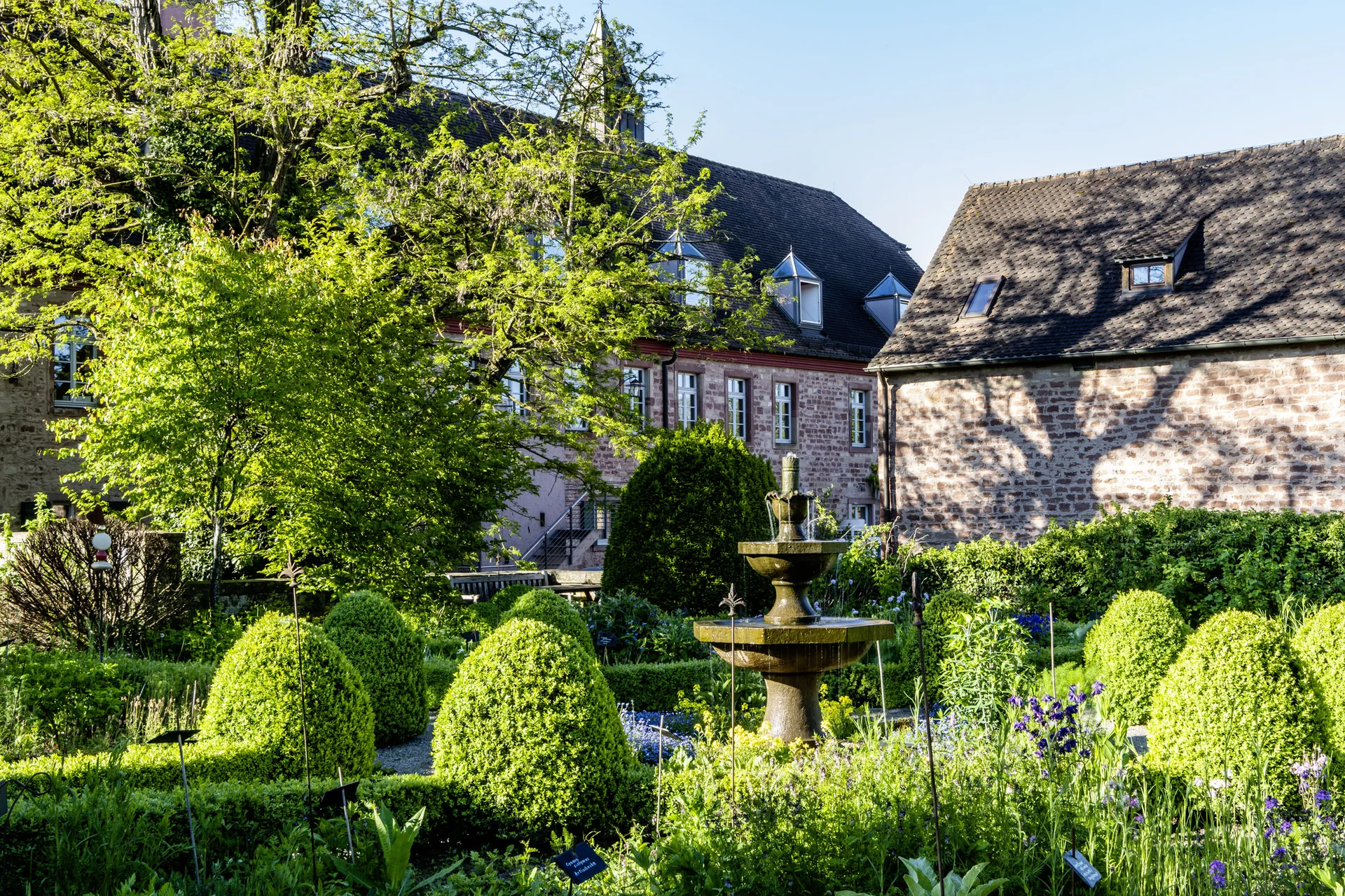 Treffpunkt, Kraftplatz und Hotel in Hornbach Historischer Garten mit Springbrunnen und Fachwerkhäusern im Hintergrund bei Sonnenschein