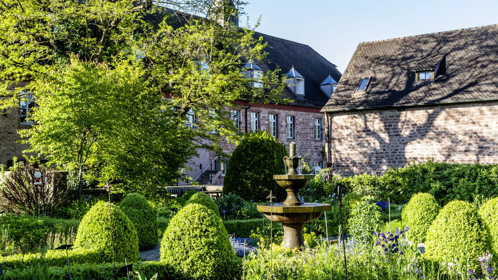 Treffpunkt, Kraftplatz und Hotel in Hornbach Historischer Garten mit Springbrunnen und Fachwerkhäusern im Hintergrund bei Sonnenschein