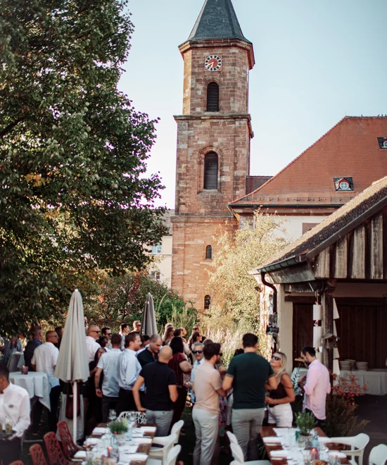 Übernachten Sie im Kloster oder im Lösch in Rheinland-Pfalz. Menschen versammeln sich im Innenhof neben einem Kirchturm bei Tageslicht