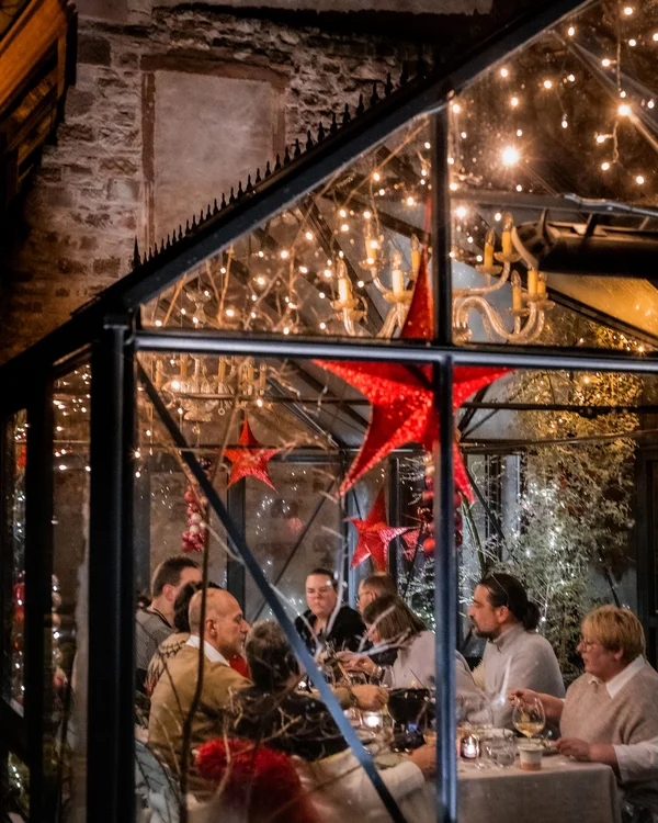 Weihnachten im Kloster Hornbach Menschen essen in einem festlich dekorierten Glashaus mit rot-leuchtenden Sternen