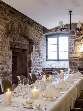 Our venue, your dream wedding Elegant dining room with stone walls and candles on a set table