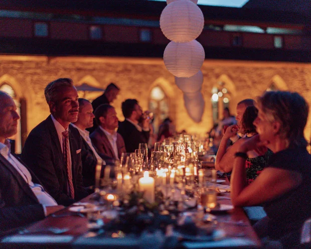 Our venue, your dream wedding Outdoor dinner with candles and lanterns, people in formal attire seated at the table