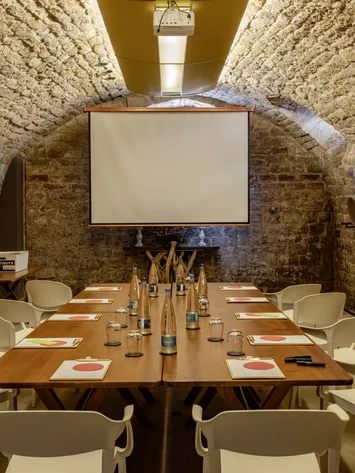 Tagungsräume Pfalz | Historische & moderne Räume im Kloster Hornbach Konferenzraum mit Steintunneldecke, Holztisch, weißen Stühlen und Projektionsleinwand