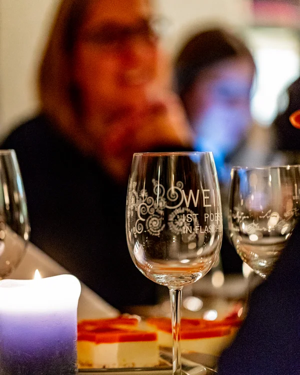 Kulinarik im Lösch: Gaumenfreuden der besonderen Art Gläser und Kerze auf einem Tisch bei einem Abendessen mit unscharfen Personen im Hintergrund