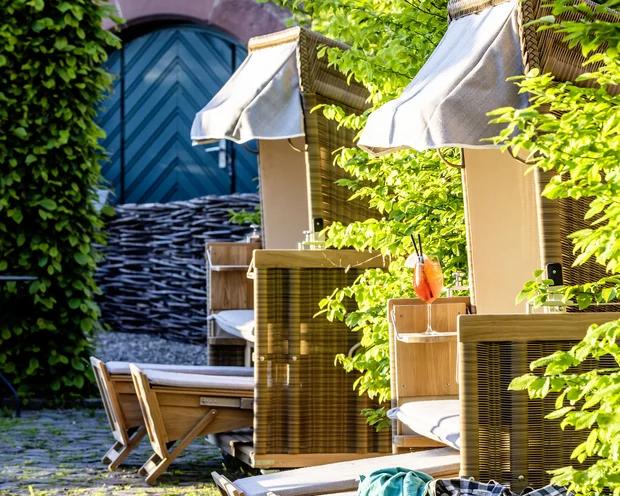 Treffpunkt, Kraftplatz und Hotel in Hornbach Strandkörbe mit Getränken und Tasche in sonnigem Garten mit altem Steinpflaster