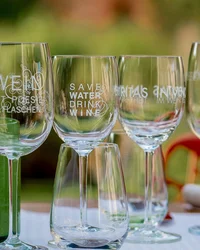 Kloster Hornbach: Ihre Ansprechperson für Medienanfragen Mehrere Weingläser mit Aufdrucken stehen auf einem Tisch im Freien