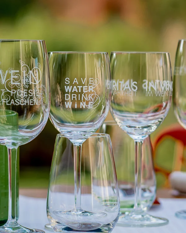 Ihr Urlaub im Klosterhotel an der Deutschen Weinstraße Mehrere Weingläser mit Aufdrucken stehen auf einem Tisch im Freien