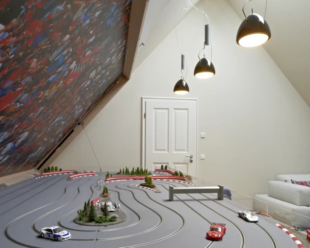 Wollen Sie das gesamte Landhaus mieten? Modell-Rennbahn mit kleinen Autos in einem modernen Raum mit Sofa und Lampen