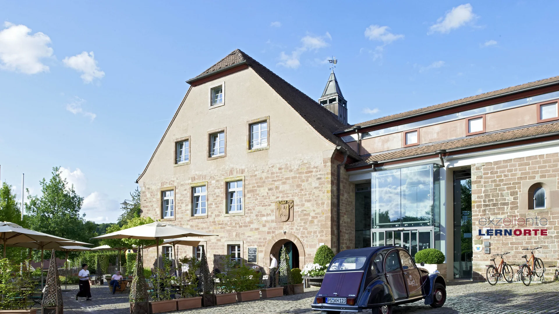 Exzellenter Lernort Kloster Hornbach Historisches Gebäude mit Außenbereich und altem Auto bei klarem Himmel