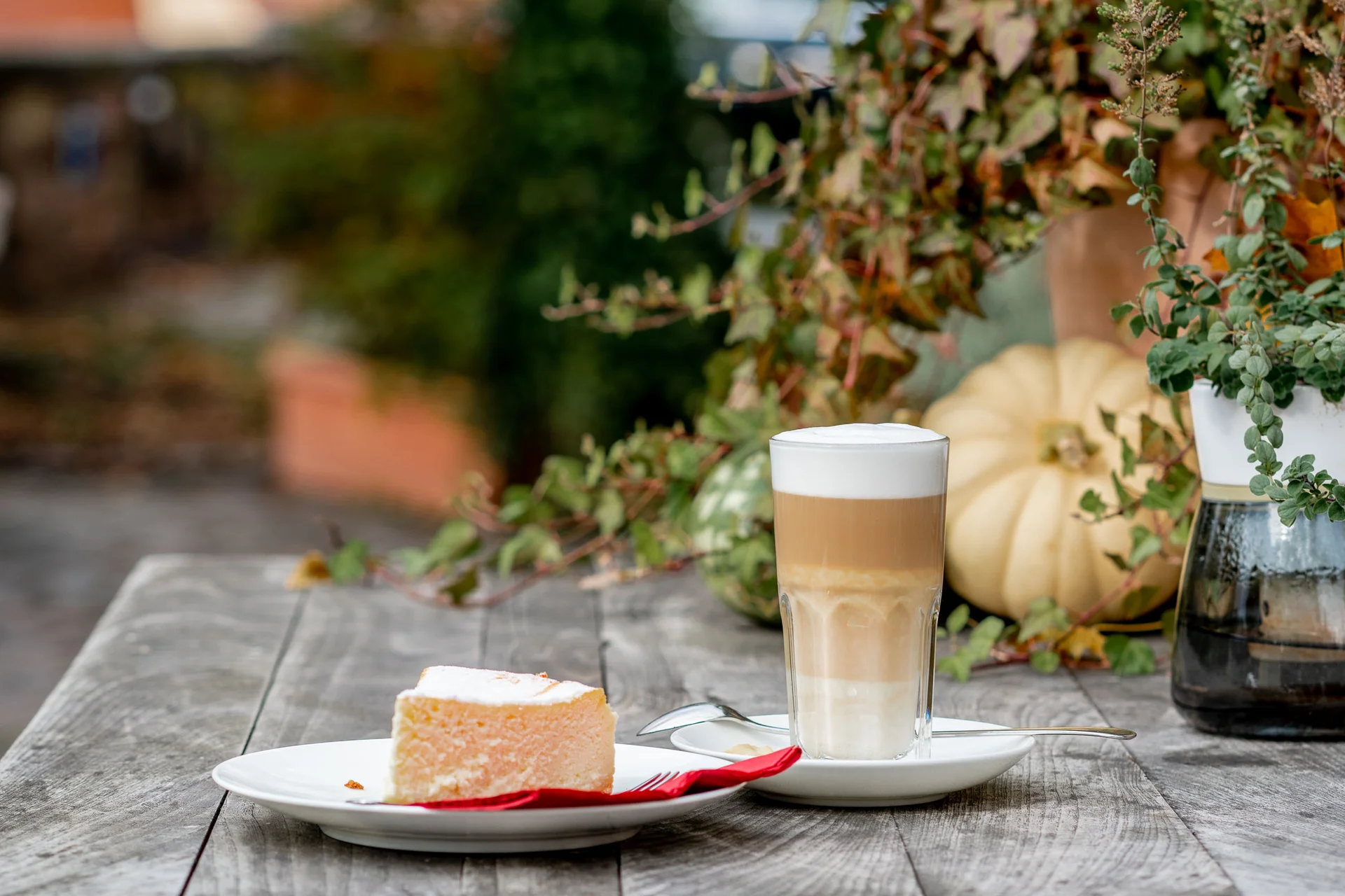 Exzellenter Lernort Kloster Hornbach Stück Käsekuchen mit Latte auf Holztisch mit herbstlicher Dekoration