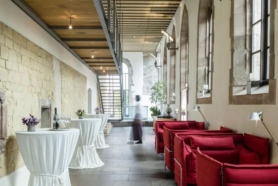 ABBA-Dinner – A Night to Remember Moderne Lounge mit roten Sofas und Stehtischen in historischem Gebäude