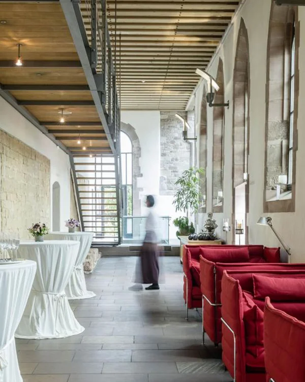 Ihre Gastgeber im Kloster Hornbach Moderne Lounge mit roten Sofas und Stehtischen in historischem Gebäude