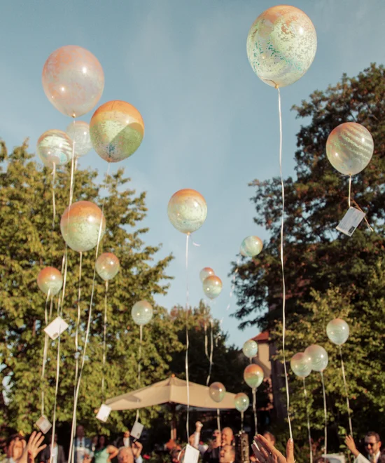 The right offer for every occasion Many balloons rising into the sky during an outdoor celebration