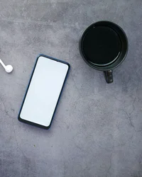 Kloster Hornbach: Ihre Ansprechperson für Medienanfragen Smartphone, schwarze Kaffeetasse, Ohrhörer und Füllfederhalter auf grauem Tisch