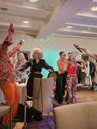Treffpunkt, Kraftplatz und Hotel in Hornbach Menschen feiern und singen mit Mikrofon auf einer Party in bunten Outfits