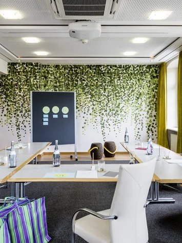 Tagungsräume Pfalz | Historische & moderne Räume im Kloster Hornbach Heller Besprechungsraum mit U-förmigen Tischen, weißen Stühlen und Blätterwanddeko