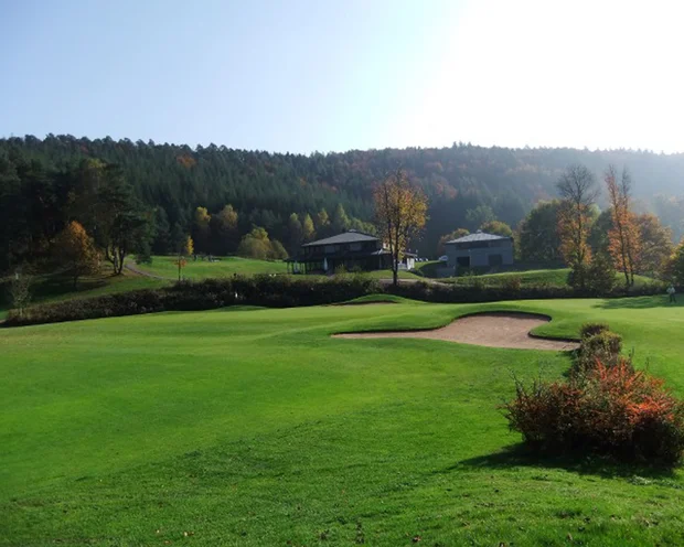 Ausflugstipps für Ihren Urlaub in der Pfalz Golfplatz mit Bunker, Häusern und Wald im Hintergrund bei sonnigem Wetter