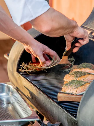Treffpunkt, Kraftplatz und Hotel in Hornbach Person legt Lachsfilets mit Kräutern auf einen Grill
