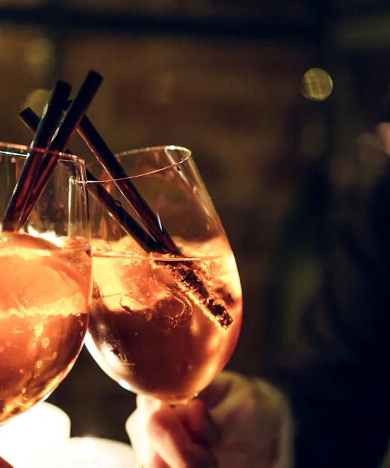 Kloster & Shopping: schöne Sachen, große Auswahl Zwei Gläser mit orangenfarbenem Getränk und schwarzen Strohhalmen bei Kerzenlicht