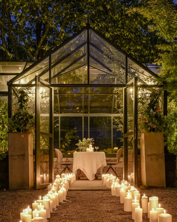 Freie Trauung in der Traumlocation in Rheinland-Pfalz Glashaus mit Kerzen beleuchtet, Weg führt zum gedeckten Tisch