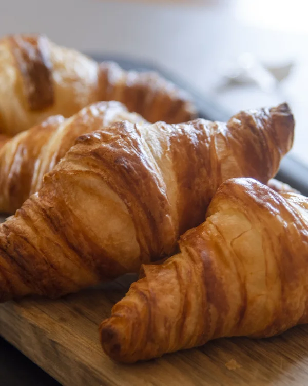 Brunch und Frühstück im Kloster bei Zweibrücken Drei frische Croissants auf einem Holzbrett neben einem Glas mit Trauben