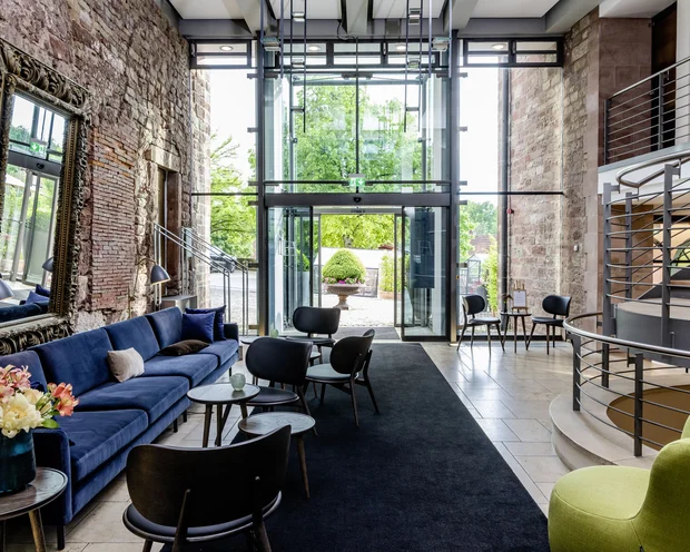 Treffpunkt, Kraftplatz und Hotel in Hornbach Moderner Wartebereich mit blauem Sofa, Stühlen und großer Glasfront mit Außensicht