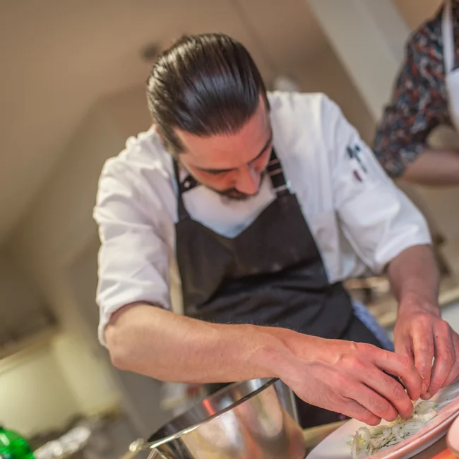 Wollen Sie das gesamte Landhaus mieten? Koch richtet sorgfältig ein Gericht auf einem Teller an