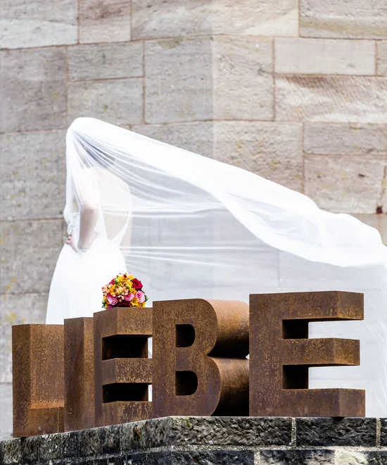 Treffpunkt, Kraftplatz und Hotel in Hornbach Braune Buchstaben leben mit Braut im weißen Kleid und Strauß im Hintergrund