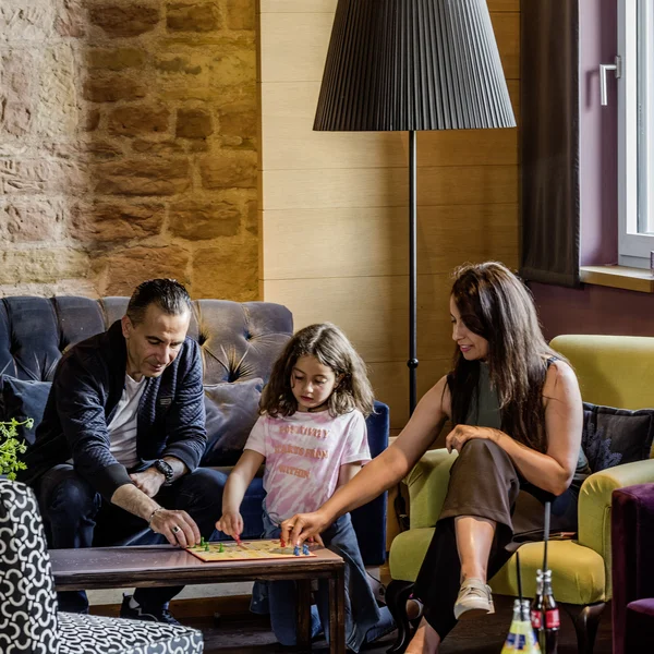 Wollen Sie das gesamte Landhaus mieten? Familie spielt Brettspiel im Wohnzimmer mit Stehlampe und Sofa