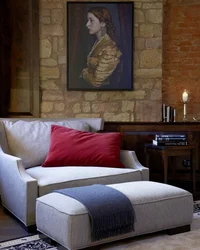 Kloster Hornbach: Ihre Ansprechperson für Medienanfragen Sitzbereich mit grauem Sofa, rotem Kissen und Gemälde an Steinwand