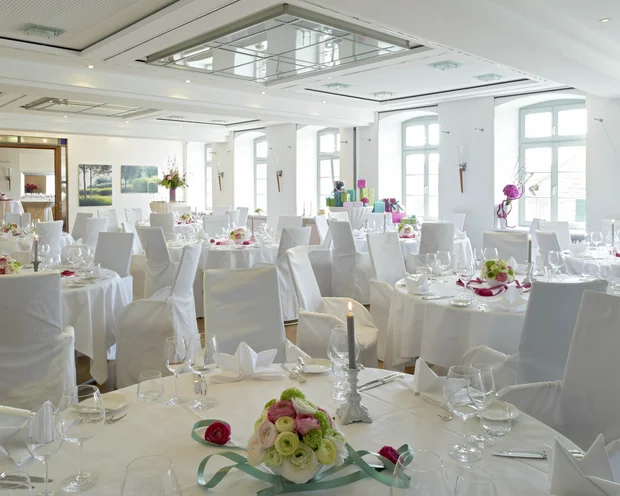 Our venue, your dream wedding Elegant wedding hall with white covered tables and floral centerpieces