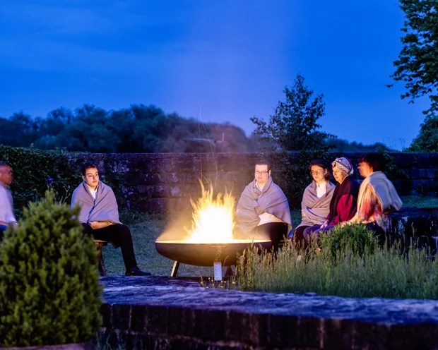 Our venue, your dream wedding People wrapped in blankets sitting around an outdoor fire pit in the evening