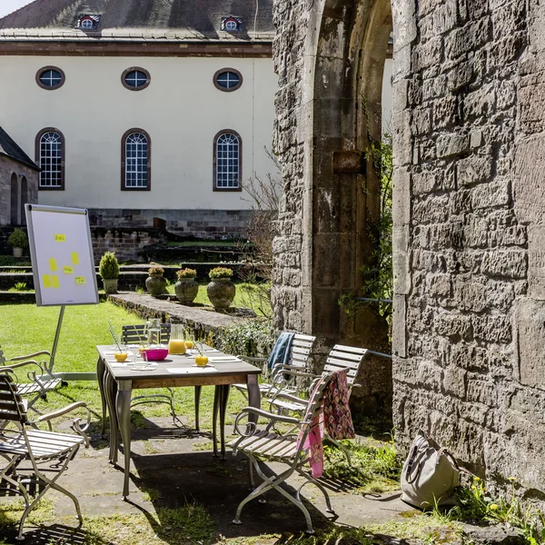 Exzellenter Lernort Kloster Hornbach Outdoor-Meetingbereich mit Tisch, Stühlen und Flipchart in historischen Mauern