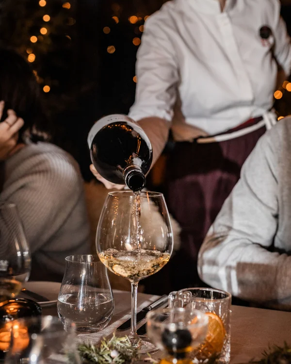 Weihnachten im Kloster Hornbach Kellner gießt Weißwein in ein Glas bei einem abendlichen Essen