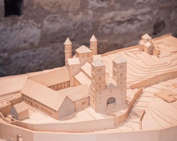 Ihre Gastgeber im Kloster Hornbach Modell eines historischen Klosterkomplexes aus Holz vor einer Steinmauer
