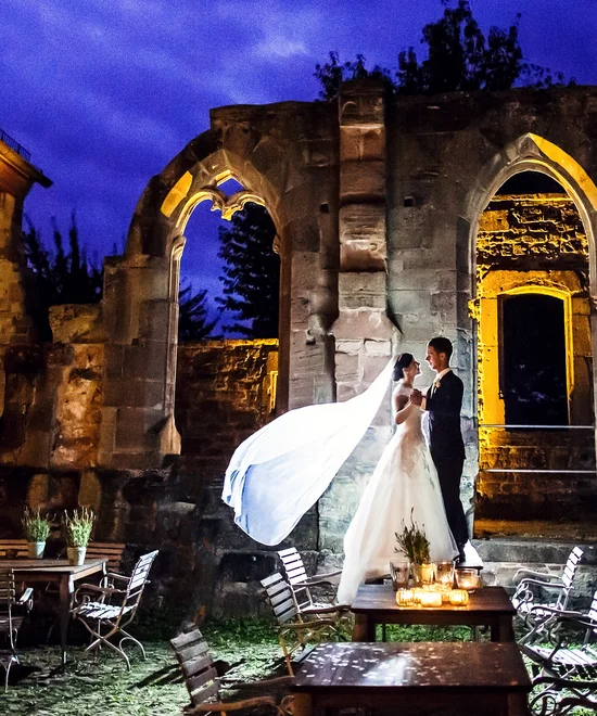 Übernachten Sie im Kloster oder im Lösch in Rheinland-Pfalz. Brautpaar bei Nacht vor beleuchteten historischen Ruinen und Tischen
